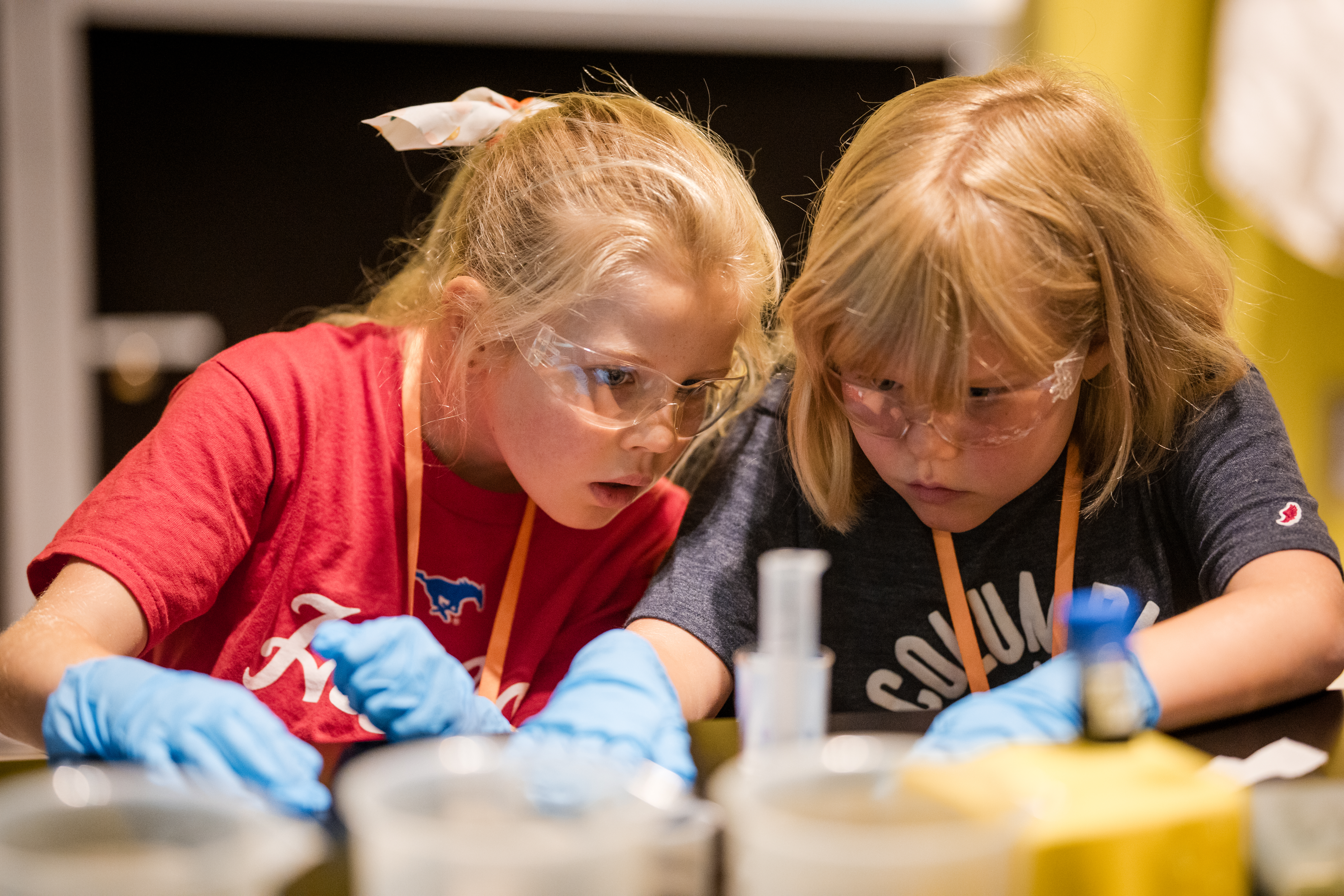 Two children wearing safety goggles and gloves doing an experiment