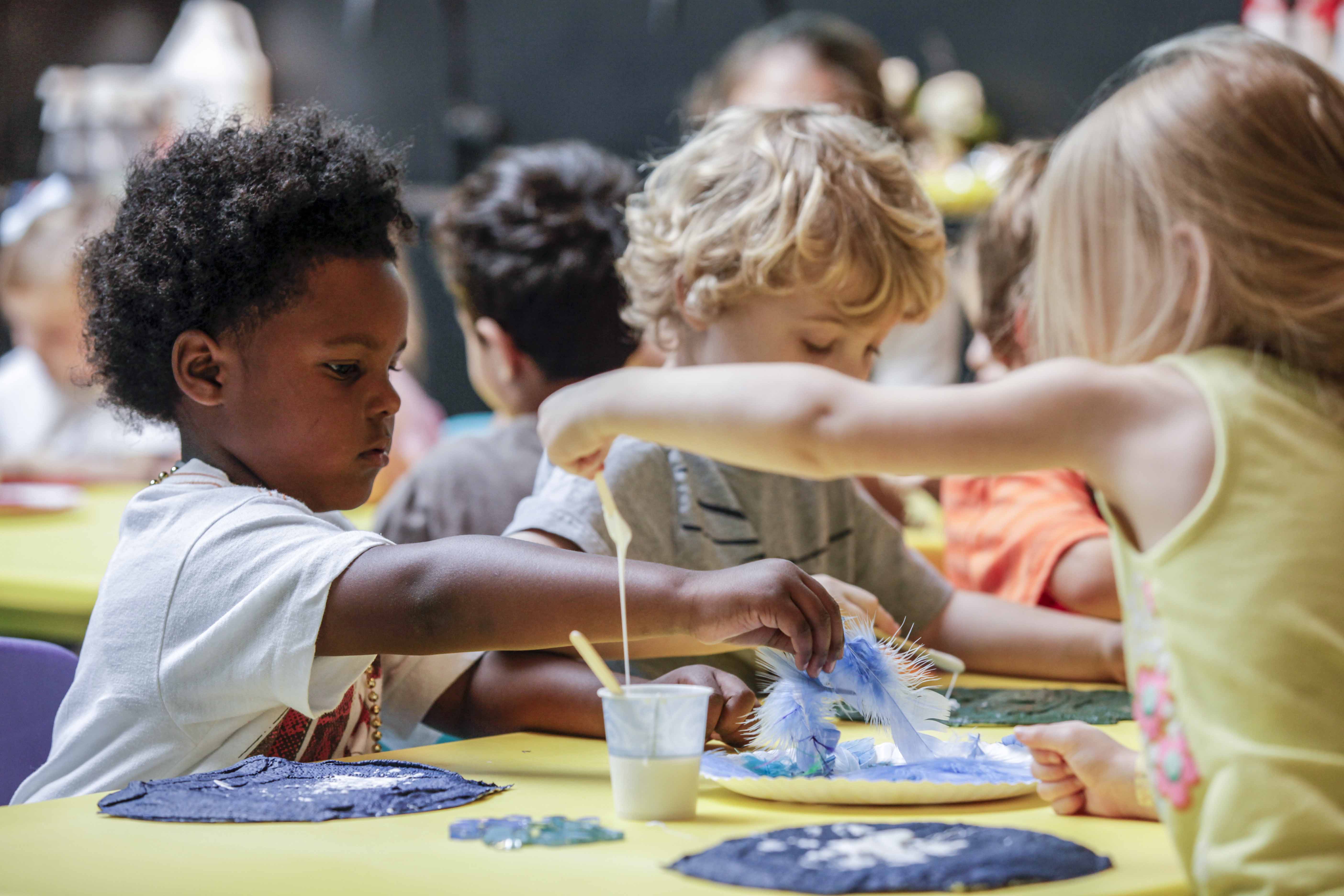 Children working at a table to create some fun artwork.