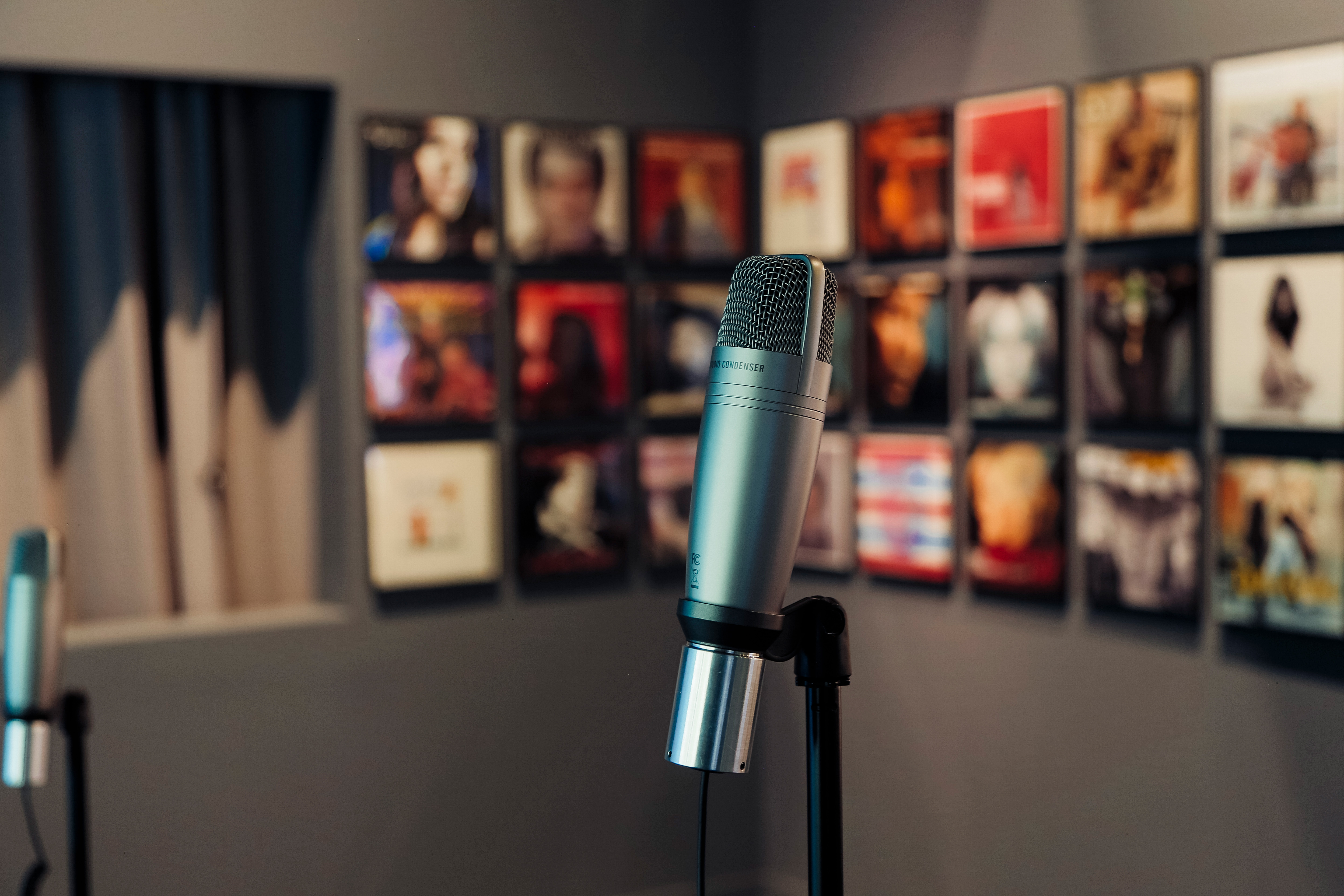 Microphone in focus with colorful album covers blurry in the background.