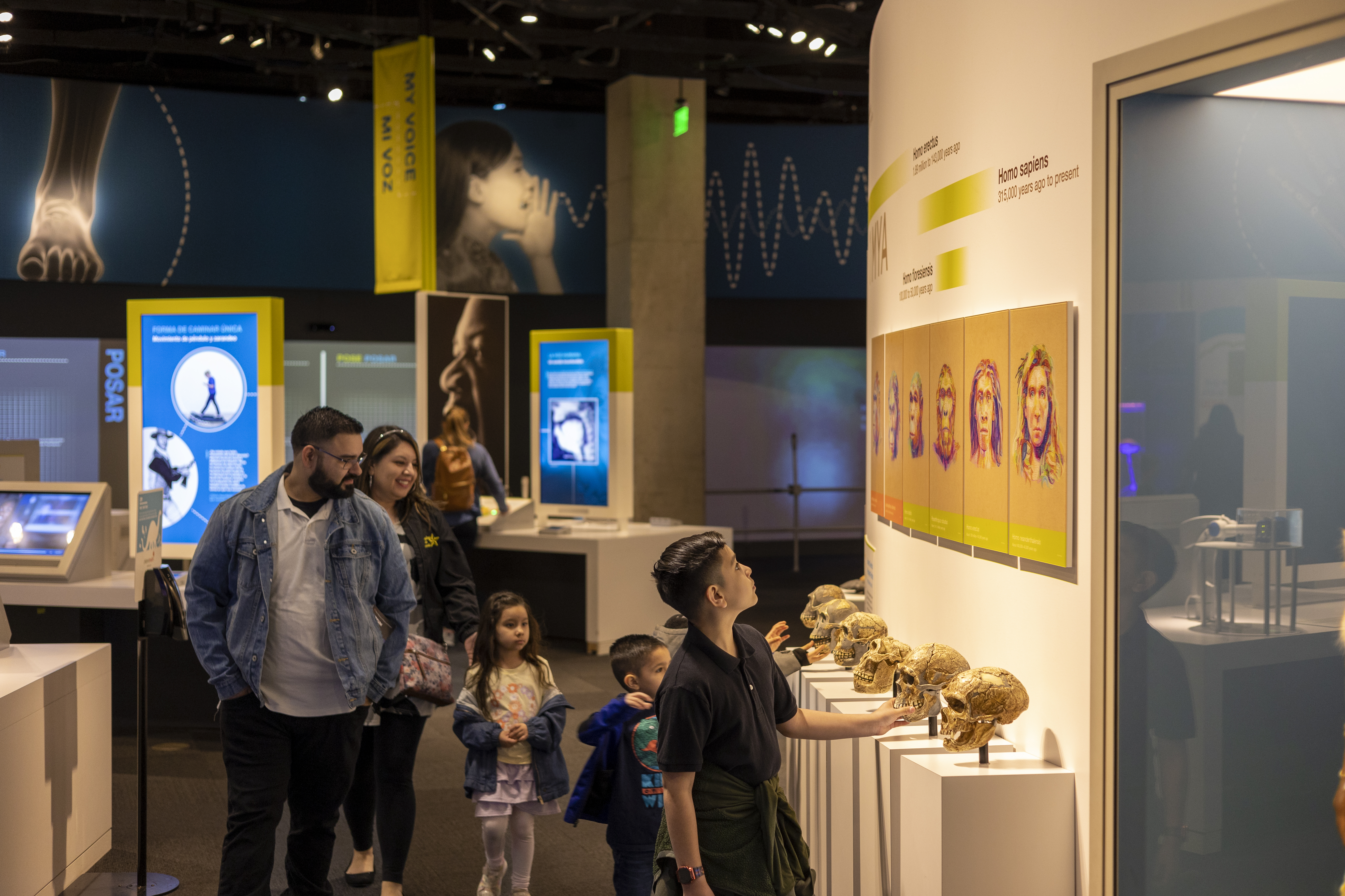 Adult man and woman with three children looking through exhibit hall with skulls