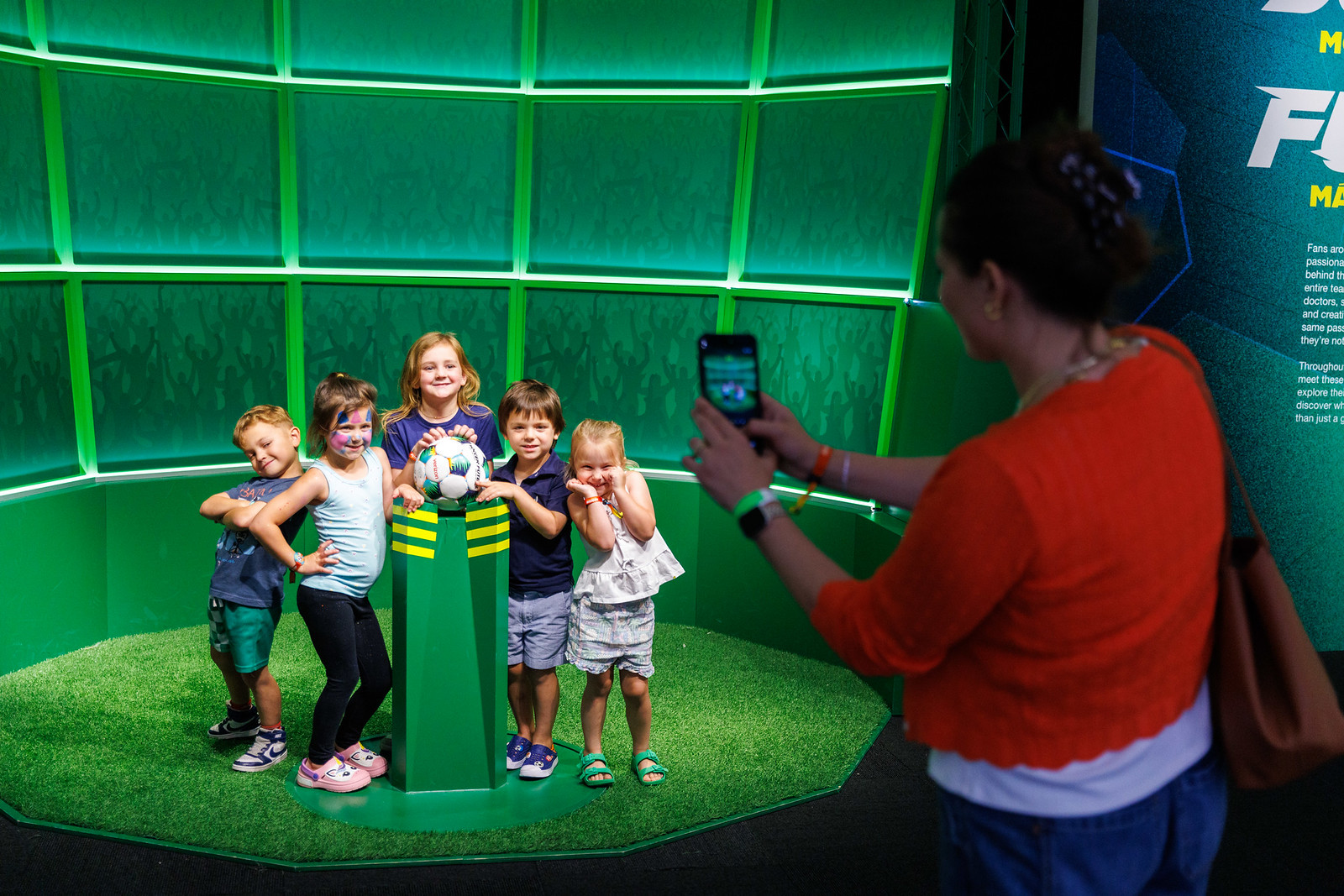Children posing behind soccer ball placed on podium