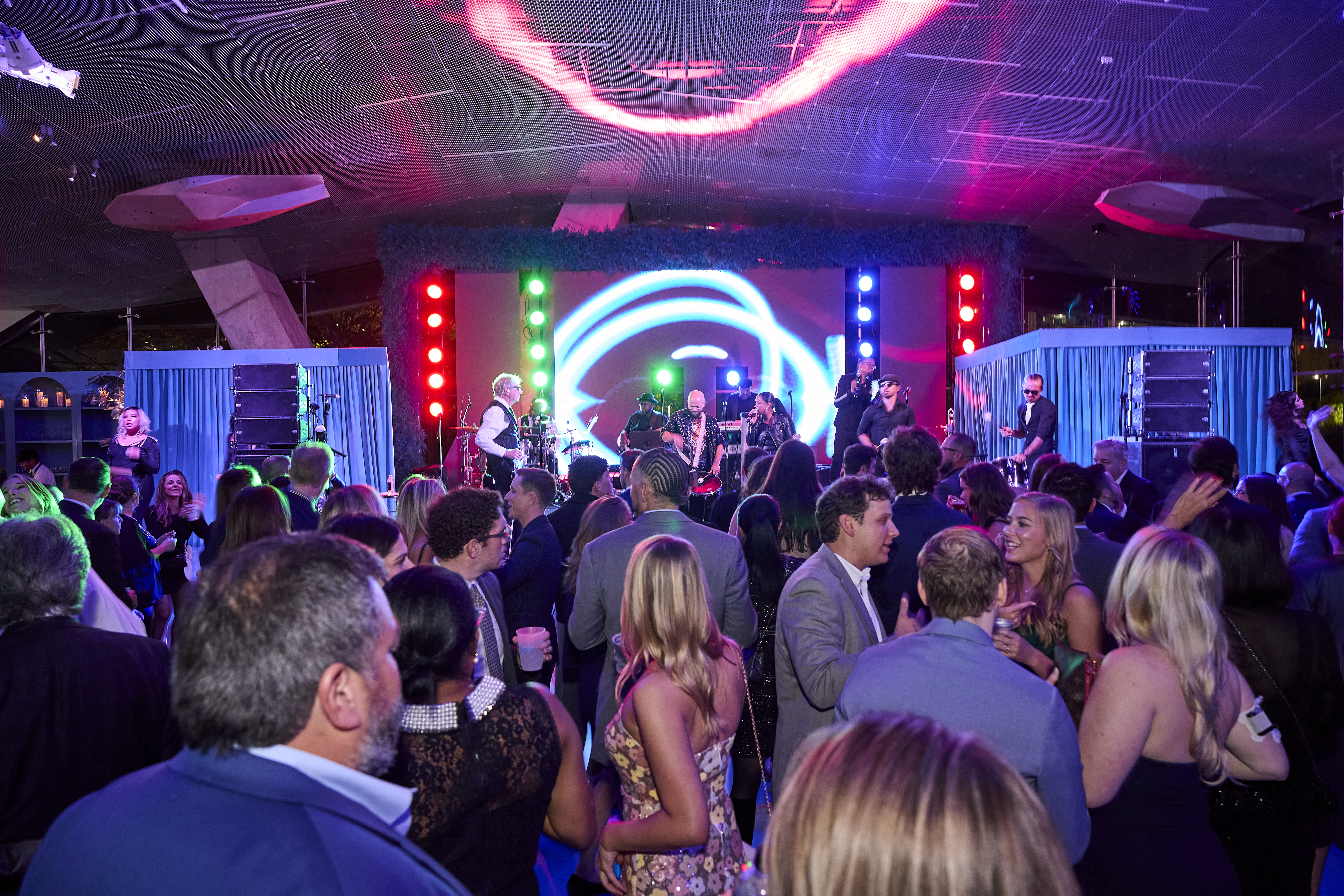 Guests enjoy party space with colorful lighting in front of a live band