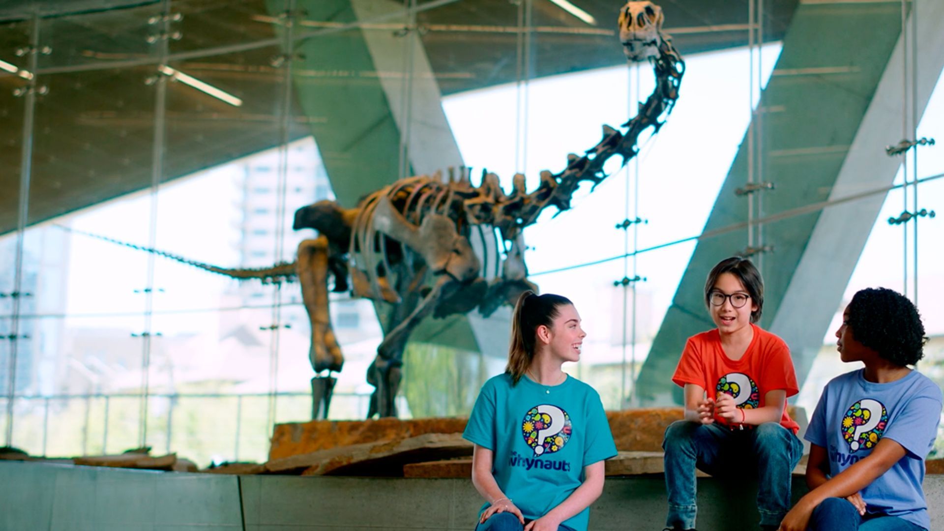 Kids sitting in front of dinosaur at Perot Museum